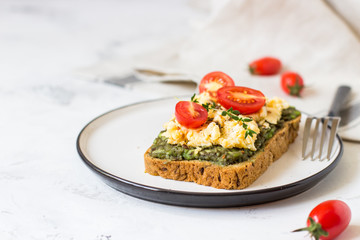 Scrambled eggs on whole wheat bread with avocado and cherry tomatoes