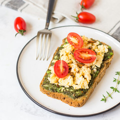 Scrambled eggs on whole wheat bread with avocado and cherry tomatoes
