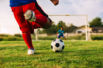 An action sport picture of a group of kids playing soccer football for exercise in community rural area under the sunset.