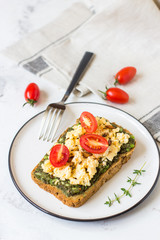 Scrambled eggs on whole wheat bread with avocado and cherry tomatoes