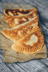 Homemade baking. Chebureks with meat and onion on wooden background.