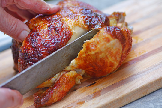 Closeup of a man slicing into a roast chicken leg