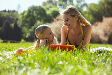 I cherish you. Cute little girl holding a tablet and talking with her mom outdoors