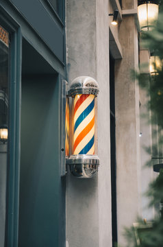 barber pole on grey wall with green wooden barber shop