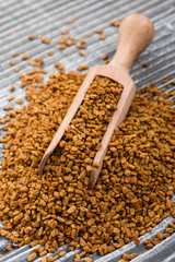 fragrant grains of fenugreek on a rustic background
