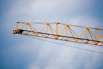 Part of a yellow construction crane and a blue sky is close up