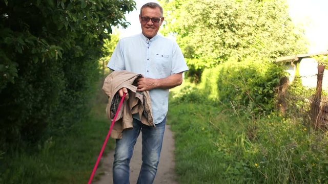 A happy male pensioner is walking his pet. The dog is happy and cheerfully bounces. Caring for pets
