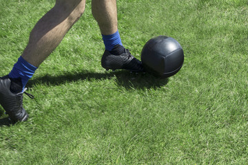 Fototapeta premium soccor player kicking abll of a green grassy field with black kelletts and balck ball