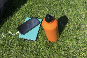 music playing on headset on a sunny day at a grass meadow park area with water bottle 