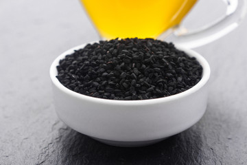 grains of black cumin and oil on the rustic background