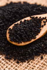 grains of black cumin and oil on the rustic background