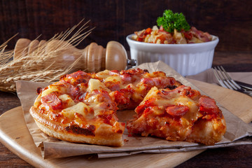 Hawaiian pizza on wood plate