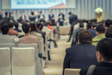 Fototapeta premium Speakers on the stage with Rear view of Audience in the conference hall or seminar meeting, business and education about investment concept
