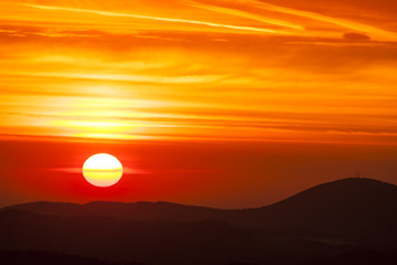 Natural Sunset Sunrise Over highland or mountains. Bright Dramatic Sky And Dark Ground. Countryside Landscape Under Scenic Colorful Sky At Daybreak Dawn. Sun Over Skyline, Horizon. Warm Colors.