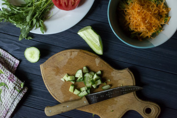 Sliced cucumber on the board with other ingredients for cooking.