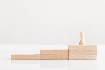 Pawn chess piece on a staircase of wooden bricks