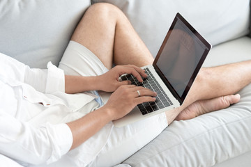 Close up man lying on sofa with laptop