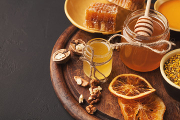 Various types of honey on wooden platter, closeup