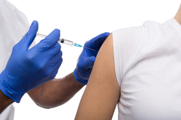 Black male hand in blue gloves holding a plastic syringe