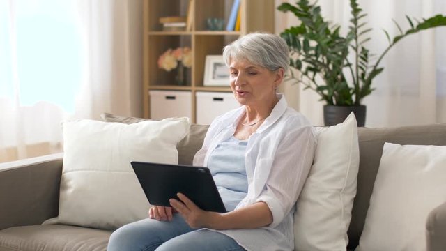 technology, people and communication concept - happy senior woman with tablet pc computer having video chat at home