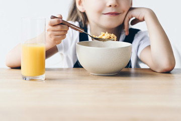 cropped shot of little schoolgirl eating healthy breakfast isolated on white