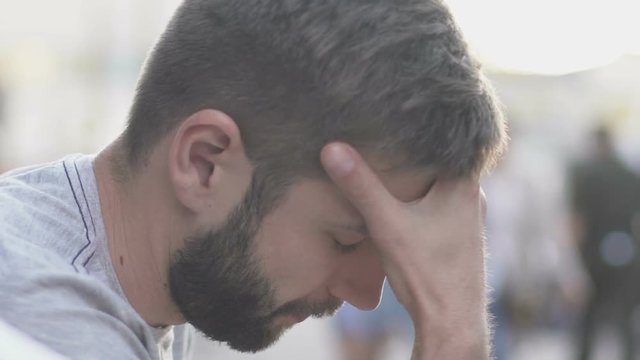 Overwhelmed man sitting in street, young male shocked by bad news, slow-mo