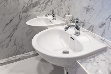 Fototapeta premium Modern faucet with wash basin sink counter marble wall bathroom interior contemporary