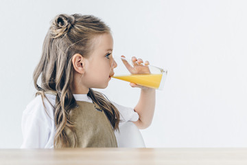 cute little schoolgirl with drinking orange juice isolated on white