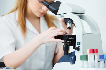 Scientist analyzing microscope slide at laboratory. Female Working in Laboratory With Microscope. Researcher examining slide. Concenrated doctor working with microscope in laboratory