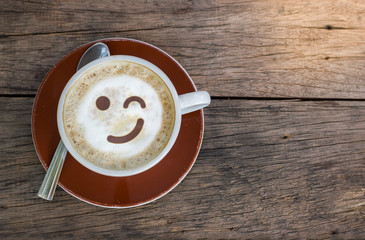 Top view of coffee cup with white foam and smile emotion face on wood texture background - Powered by Adobe