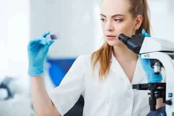 Scientist analyzing microscope slide at laboratory. Female Working in Laboratory With Microscope....