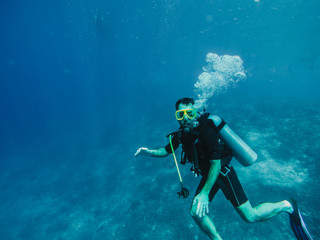 .Young tourist diving in the Gili island, Indonesia, many meters deep, discovering the wild life of the seabed. Lifestyle and travel concept.