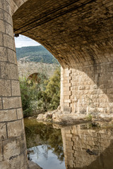 Look at the archway of one bridge to the arches of another bridge. River under the bridge and reflection in it.