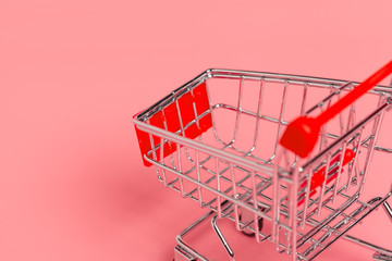 Shopping cart or supermarket trolley on pink background