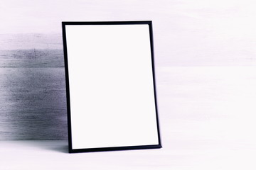 Empty blank layout photo frame on a white wooden background. Front view, copy space, mock up 