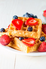 Photo of fresh homemade food made of berry Belgian waffles with honey, chocolate, strawberry, blueberry, maple syrup and cream. Healthy dessert breakfast concept with juice. 