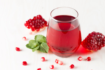 A glass of pomegranate juice with fresh pomegranate fruits on wooden table. Vitamins and minerals. Healthy drink concept.