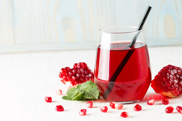 A glass of pomegranate juice with fresh pomegranate fruits on wooden table. Vitamins and minerals. Healthy drink concept.