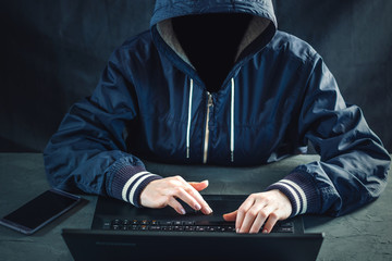 Anonymous hacker uses a laptop to hack the system. Stealing personal data. Creation and infection of malicious virus.