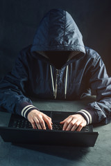 Anonymous hacker programmer uses a laptop to hack the system. Stealing personal data and infection...