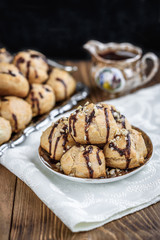 Profiteroles is a delicious culinary dishes of French cuisine with chocolate icing and nuts. Delicious profiteroles dessert on plate on dark wooden background.