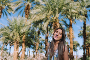 Holidays woman smiling at camera on tropical beach summer vacation with palm trees and date palms