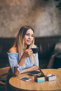 Young hispanic woman at cafe drinking coffee 