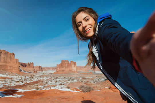 Female traveller taikng self portraits with rock formation in the Arches National Park, Utah, USA