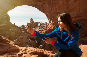 Female traveller taikng self portraits with rock formation in the Arches National Park, Utah, USA