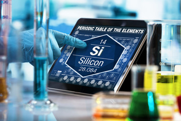 scientist consulting on the digital tablet data of the chemical element Silicon Si / researcher...