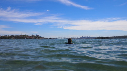 Man with diving mask and snorkel in front of Sydney harbor bridge and skyline, aquatic adventure at Sydney inner harbor