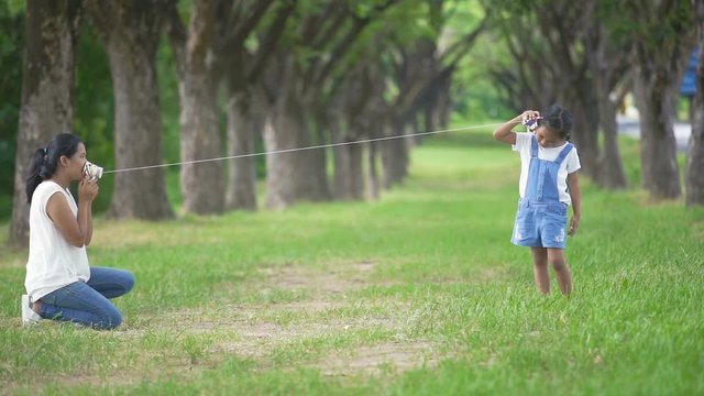 Slow motion, Asian family, mother and daughter doing string phone play activities tie rope at the park.