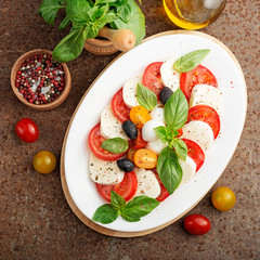 Delicious caprese salad with  tomatoes,mozzarella cheese and fresh basil leaves. Italian food. top view