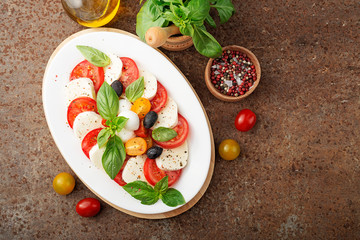 Delicious caprese salad with  tomatoes,mozzarella cheese and fresh basil leaves. Italian food. top view